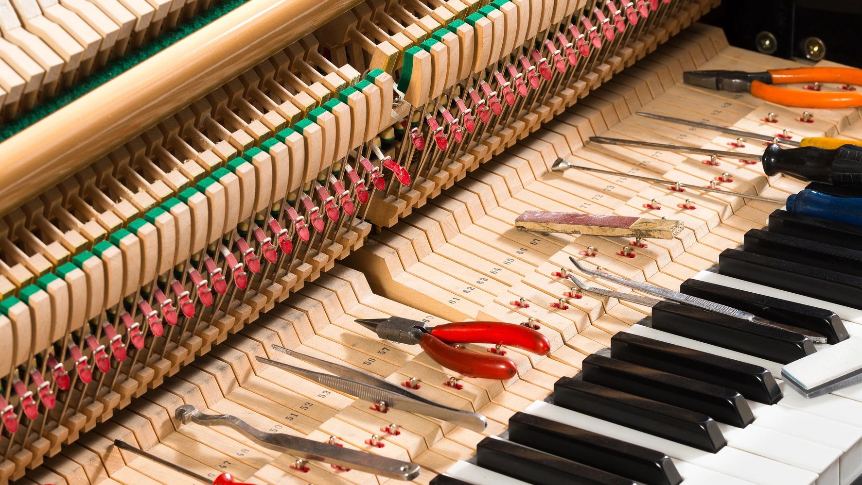 Inside view of an upright piano with tools for repair.