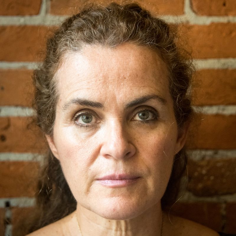 Mature caucasian woman looking at the camera on a brick wall background