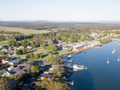 Aerial view of a riverside town with boats and greenery.