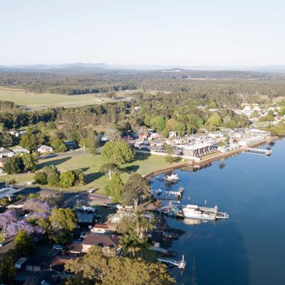 A peaceful riverside town with docks and greenery under clear skies.