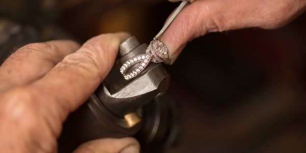 Hands examining a diamond ring under light.