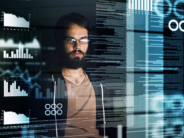 Bearded man analyzing digital data and charts on transparent screens.