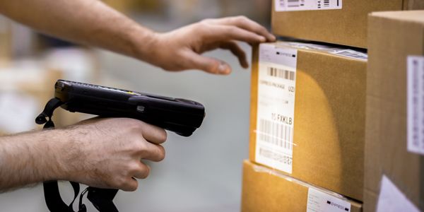 Hand scanning a barcode on a package with a barcode scanner.