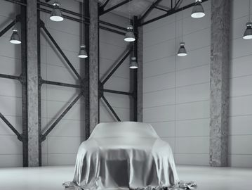 A car covered by a silver cloth in a modern garage.