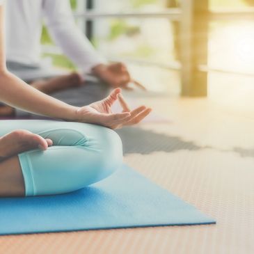 Person meditating on a yoga mat in a serene setting.