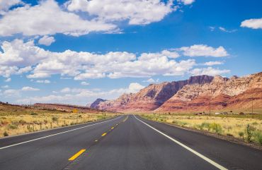 Open road through desert landscape under a blue sky.