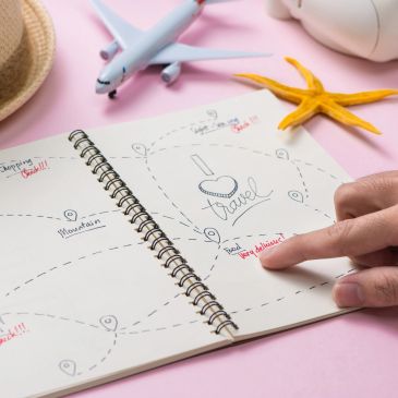 Travel planning in a notebook with a toy airplane and starfish.