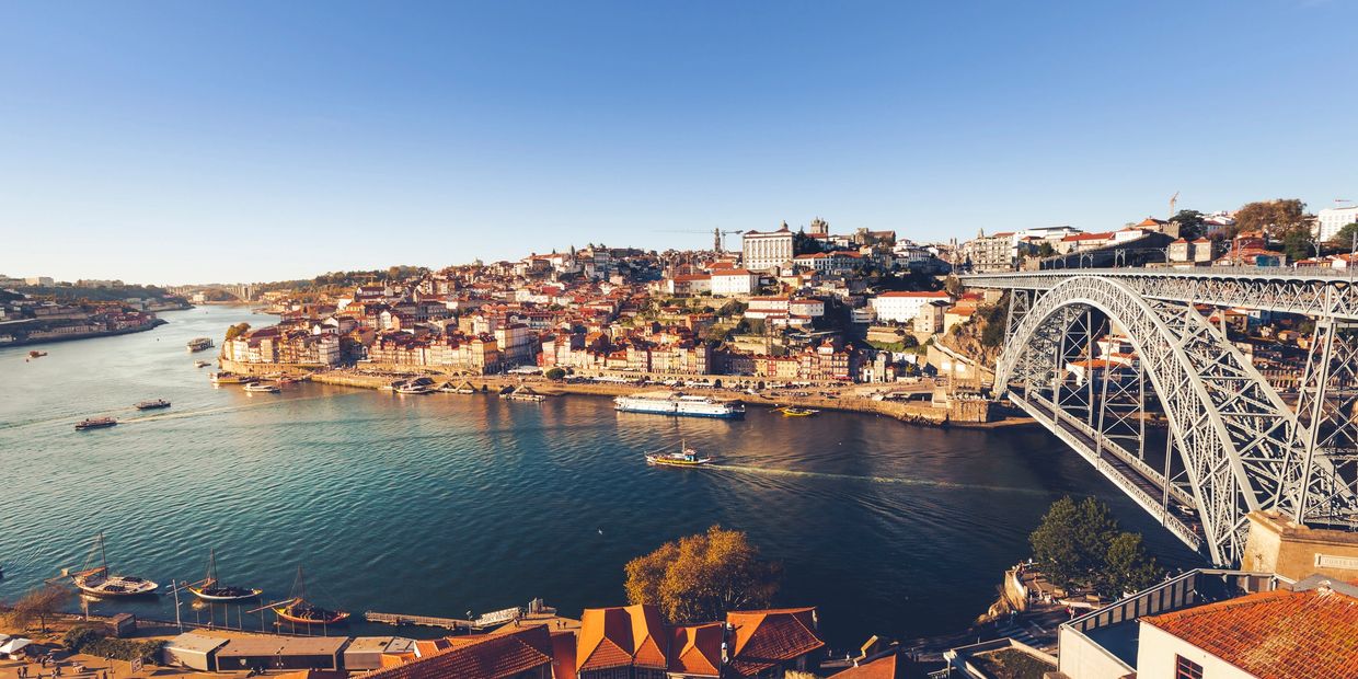 Scenic view of a city by the river with a large bridge.