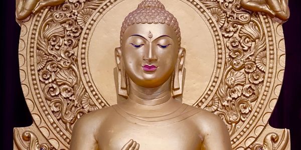 Golden Buddha statue with intricate floral halo and serene expression.