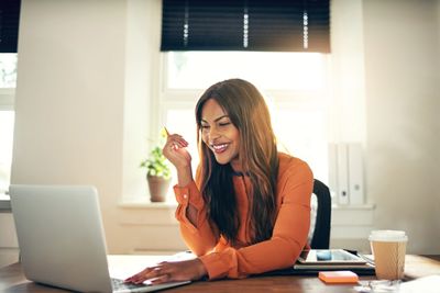 Smiling woman working on a laptop in a bright office.