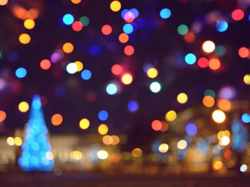 Colorful blurred bokeh lights with a blue Christmas tree.