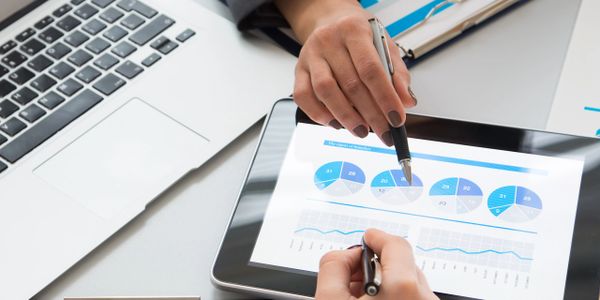 Two people analyzing charts and data on a tablet and clipboard.