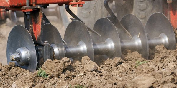 Close-up of a disc plow tilling soil.