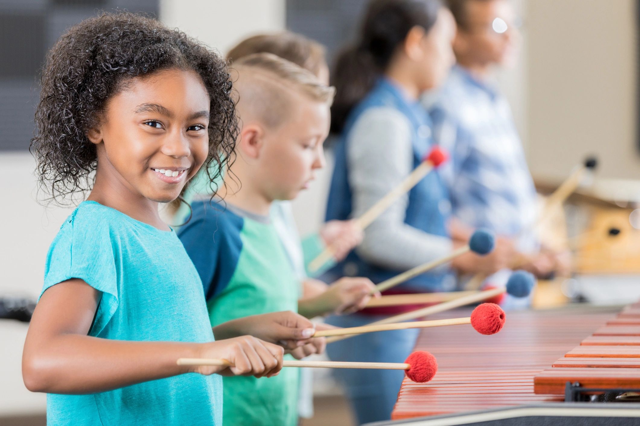 Children playing xylophones with mallets in a music class.