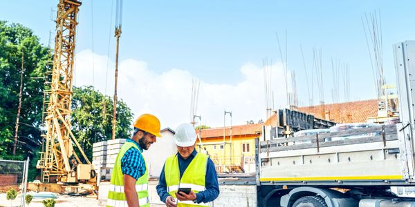Construction worker standing on wooden frame of building under clear sky.