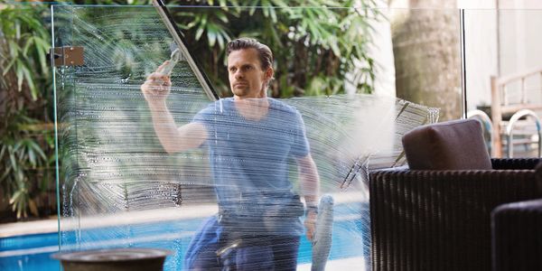 Man cleaning a large glass window with a squeegee outdoors.