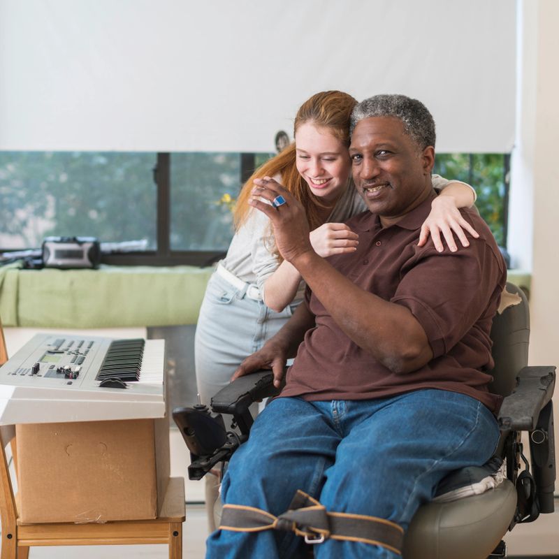 Pretty Caucasian White teenager girl hugging the Black disabled veteran who sitting in wheelchair