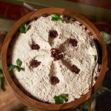 A bowl of creamy dessert garnished with berries and parsley.