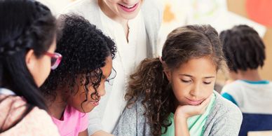 Children studying in the class room and woman seen from behind