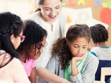 Teacher helping students with a book.