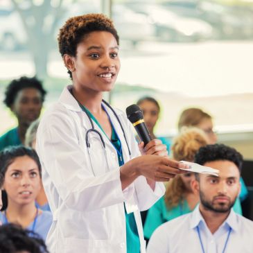 Doctor speaking into a microphone during a presentation.