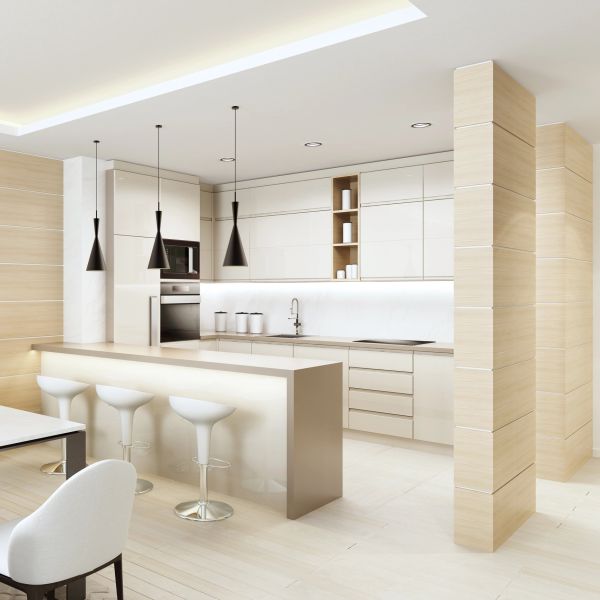 Modern kitchen with white cabinets and black pendant lights over a beige island.
