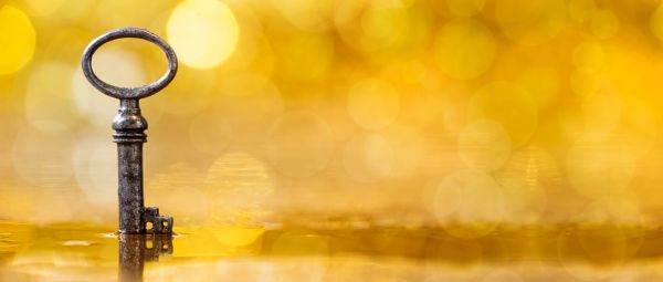An old key stands upright against a golden bokeh background.