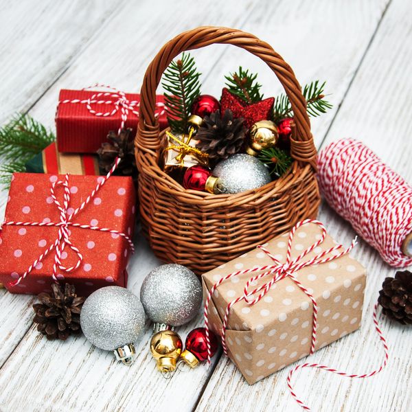 Christmas gifts, ornaments, and pine cones arranged on a white wooden surface.