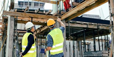 Two construction workers in safety gear inspecting a building framework.