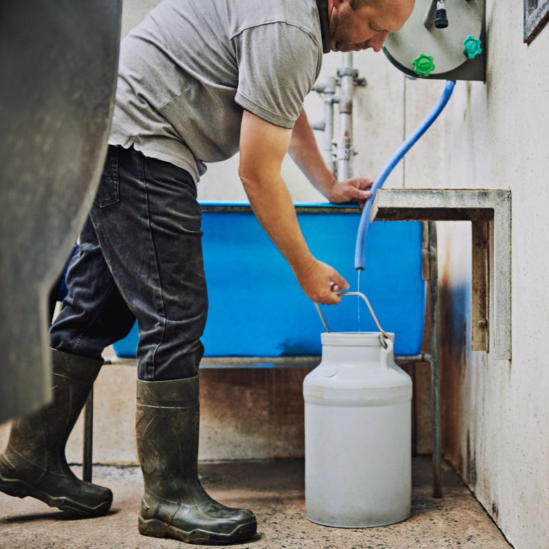 Cropped shot of a male farmer filling up a canister with water on his dairy farm