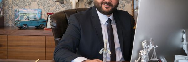 Confident man in a suit working at a desk with legal symbols and a computer.