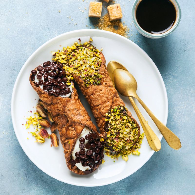Cannoli with ricotta, chocolate and pistachios. Italian pastries of the Sicily . classic breakfast with orange juice and coffee