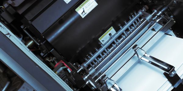 Close-up of a printing press machine with paper loaded.