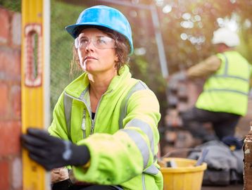 Female construction worker measuring a surface.