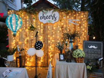Cozy photo booth setup with warm lights, balloons, and rustic decor.