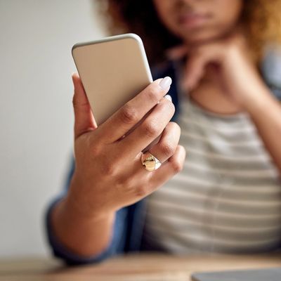 Person holding a smartphone, focusing on hand and ring.