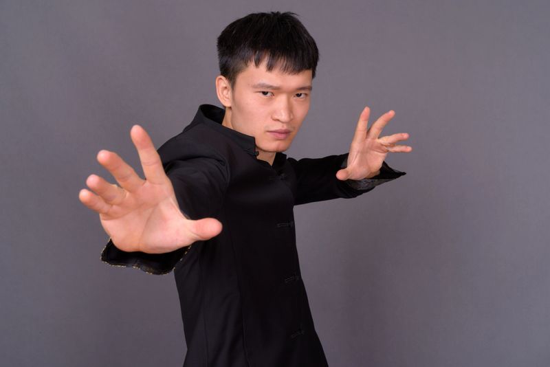 Studio shot of young Chinese man wearing traditional clothes against gray background