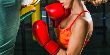 Woman in red boxing gloves training with a punching pad.
