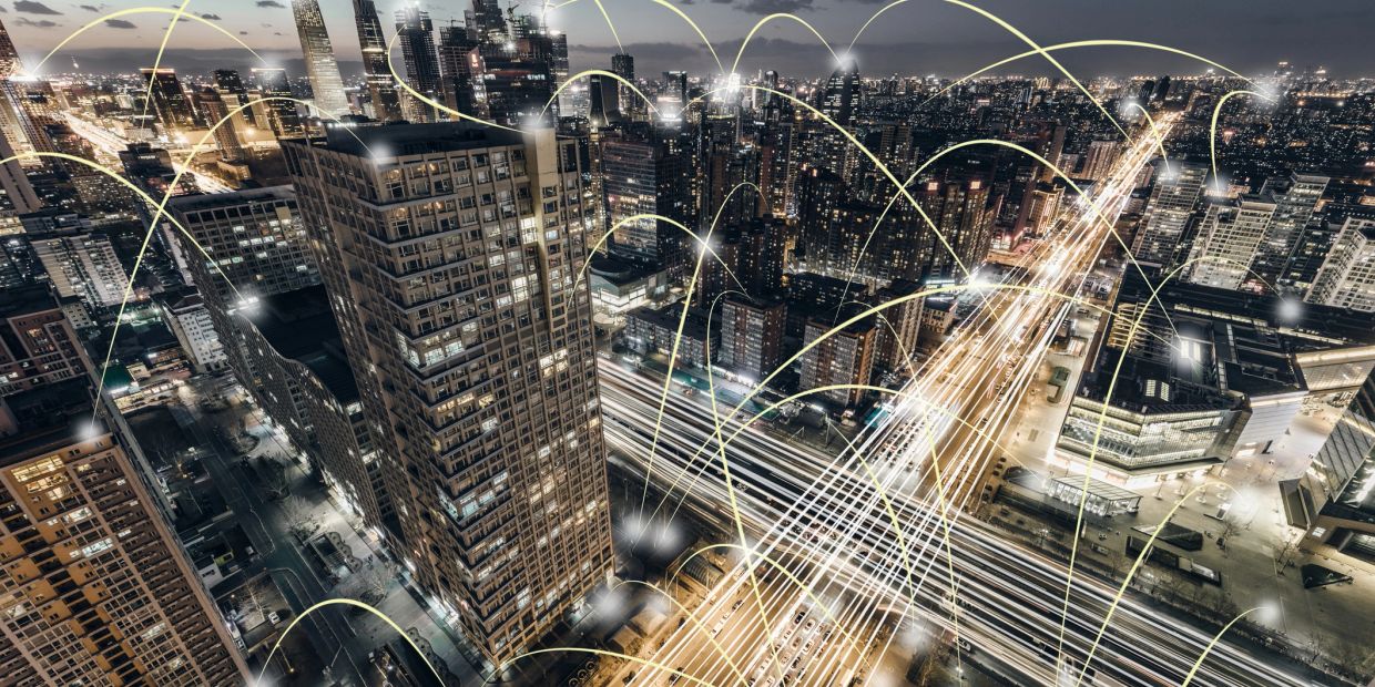 City skyscrapers connected by digital network lines at night.