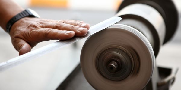 Large knife being polished on a traditional buffing wheel