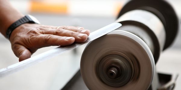 Large knife being polished on a traditional buffing wheel