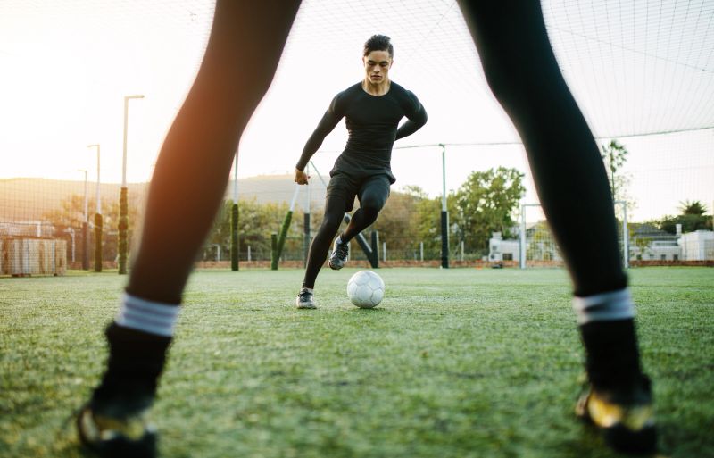 Soccer players during practice on football ground. Young footballer playing on the grass field.