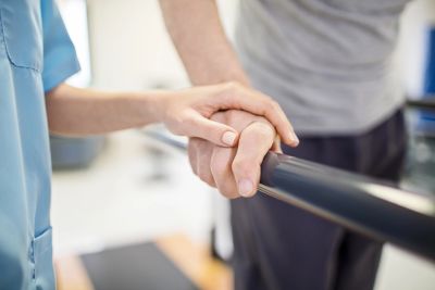 Caregiver holding patient's hand for support.