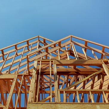 Wooden house frame under clear blue sky.
