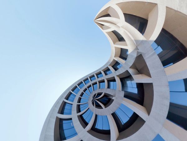 Abstract spiral effect on a modern building's facade with blue windows.