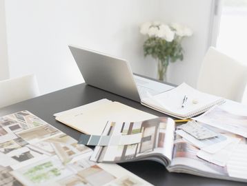 Workspace with laptop, open magazines, and color swatches on a black table.