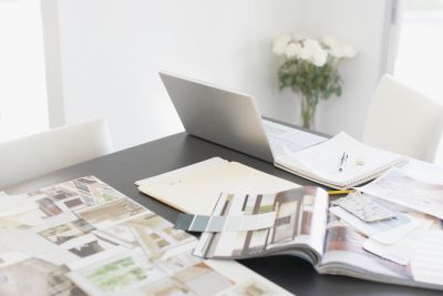 Workspace with laptop, notebooks, and design materials on a black table.