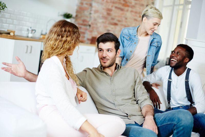 Two happy young couples talking during gathering at home on weekend