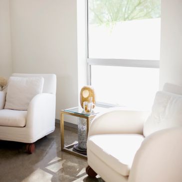 Bright room with white chairs and a glass side table.