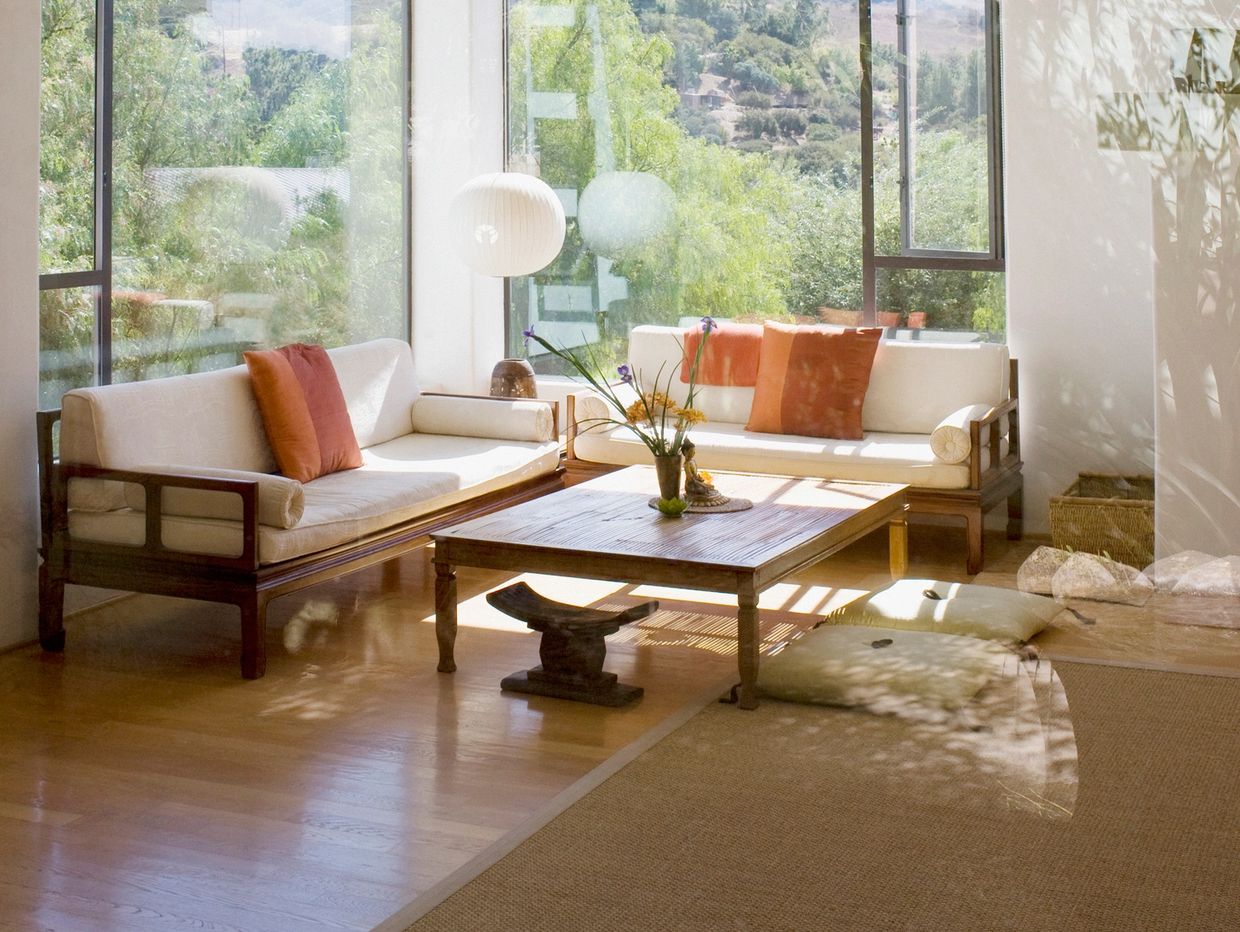 Bright living room with large windows and orange cushions.